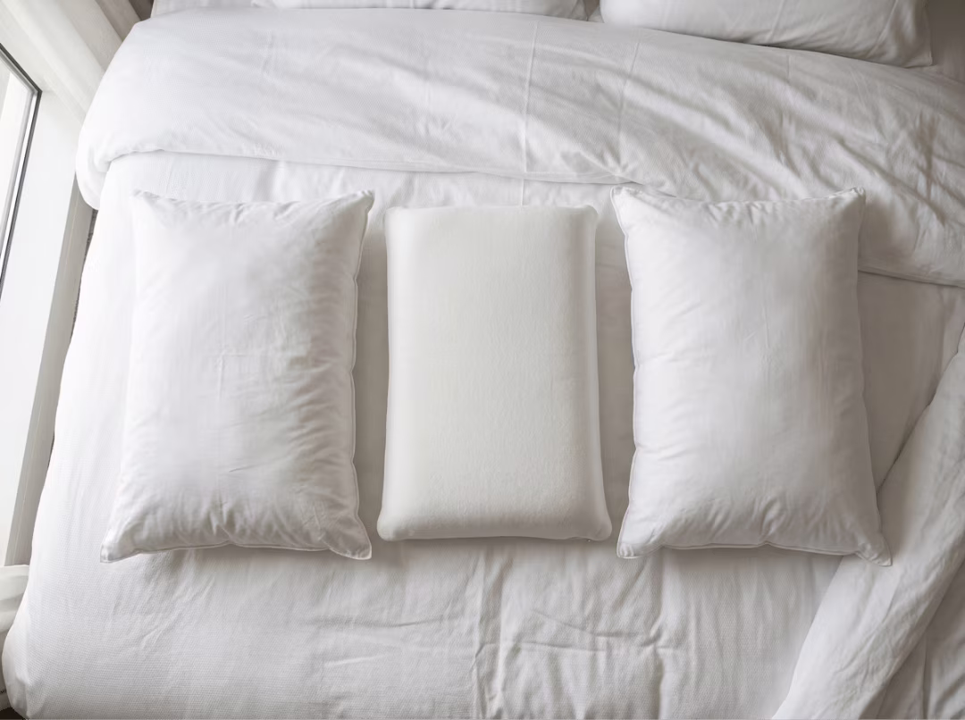 Assorted hotel pillows on white bedding Assorted hotel pillows on white bedding